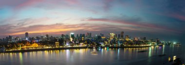 Kamboçya 'nın başkenti üzerindeki altın artçı ışıltı, işlek Riverside ve ünlü simgeler ve batan güneş Tonle Sap nehrinin arkasından batarken Kraliyet Sarayı..