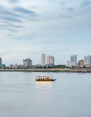 Kamboçya 'nın başkentinin simgelerini ve Mekong Nehri' ni görmek için turistleri yukarı ve aşağı taşırken güneş battı. Kurak mevsimde hava kararmadan önce mavi saat..