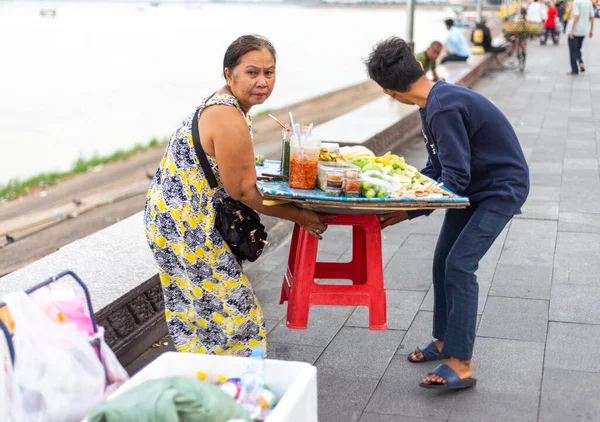 2023年1月4日カンボジア プノンペン 女性ベンダーが支援を受け 小さな果物のディスプレイを別の場所に持ち上げ 川岸の壁に沿って果物スナックを販売する — ストック写真