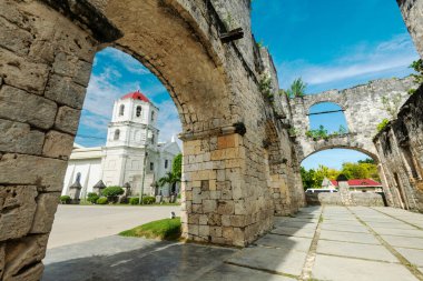 Relics of Spanish colonialism in Cebu,both built in the 1800's from coral stones,the ruins to house Spanish troops,the pretty church still active,a major tourist spot and top heritage site in Oslob. clipart