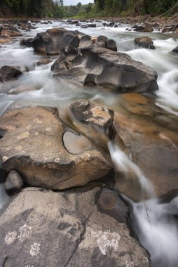 Vang Ngao nehri boyunca güneşin ışığında parlayan, karanlık kayaların üzerinde akan, tatlı dağ suyunun uzun süre maruz kaldığı hareketlilik..
