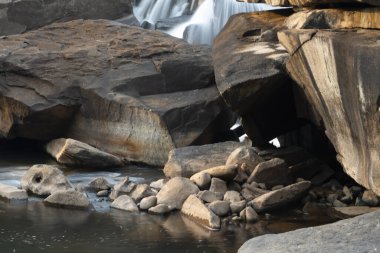Pakse Döngü rotasında, harika kaya oluşumları ve büyük parlak kayalar üzerinde uzun pozlu su hareketi, Vang Ngao Nehri boyunca gün batımına bakıyor.