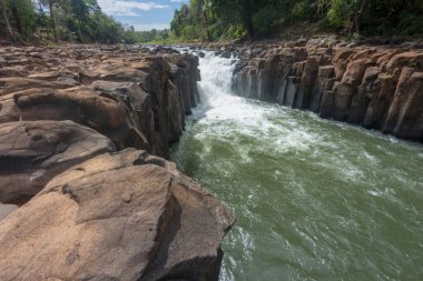 Vang Ngao nehri boyunca güneşin ışığında parlayan, karanlık kayaların üzerinde akan, tatlı dağ suyunun uzun süre maruz kaldığı hareketlilik..