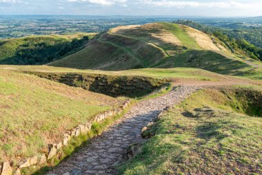 Malvern Hills 'in güney ucunda, Hereford Beacon zirvesinden aşağıya doğru inen taş basamaklar, antik yamaçtan Gloucestershire' a kadar uzanan güzel manzaralı, güneşli, İngiliz yaz mevsiminde bir öğleden sonra,.
