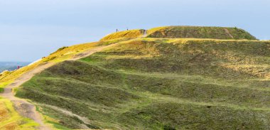 Güneş batarken, uzak bir insan figürü eski Demir Çağı tepe kalesinin zirvesinde duruyor, güzel bir yaz günü batıya bakıyor..
