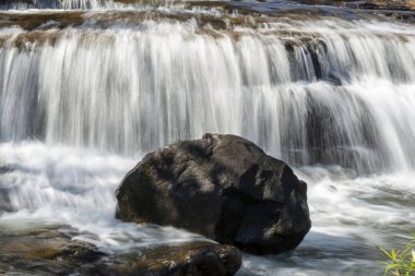 Güney Laos 'un Bolaven Platosu' nda, küçük bir köy olan Tad Lo 'ya yakın bir yerde, güzel orta büyüklükteki şelaleler ve ön planda güneşli kayalar vardı..