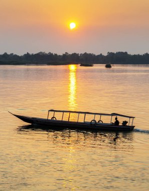 Kayaklardaki iki insan figürünün siluetleri Mekong 'un sakin ve huzurlu sularında yüzüyor. Güney Laos' taki güneşten gelen, suya, batan güneşe yansıyan altın ışık ışınları aracılığıyla..