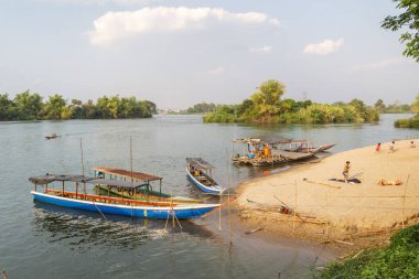 ,4000 ada, Si Phan Don, Khong Bölgesi, Laos-21 Şubat 2023: Gezginler, Nakasong ve Don Som Adaları 'na giden ve buraya gelen küçük tahtadan botlar, Mekong Nehri sahilinde dinleniyorlar..