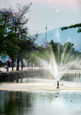 Su fıskiyeleri, Tayland 'ın kuzey başkentinin Eski Şehir Bölgesi' nin etrafını çevreleyen su kütlelerine su sıçratır. Arka planda dumanlı dağların üzerine kurulmuş trafik devam ediyor..