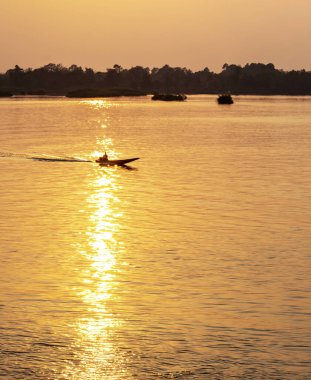 Mükemmel Lao gün batımı, nehir tekneleri Mekong 'un sakin sularında, Si Phan Don takımadalarında, nehir sularından yansıyan altın ışık ışınları aracılığıyla yüzerler..