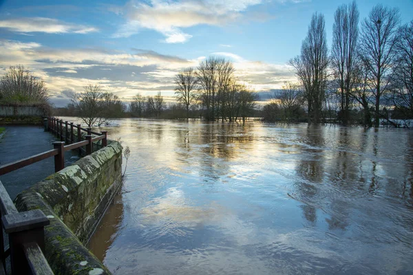 Significant flooding from rain water pouring into the Severn river,covering fields and pathways, from sourounding hills and countryside after prolonged winter,New Year precipitation,at sunset.