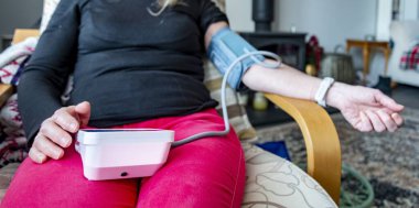 Orta yaşlı bir kadın, kendi kan basıncını ölçüyor, Worcester, Worcestershire, İngiltere, İngiltere.