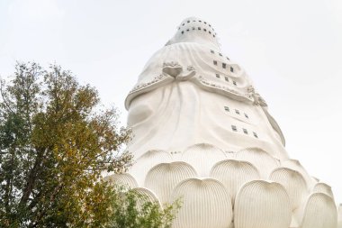 Günbatımındaki devasa, içi boş yapıya havalandırma sağlayan birden fazla açık pencere. Ziyaretçiler, tapınak kompleksinin üzerinde yükselen ikonik Budist binasının içinde asansörle, kafaya kadar girebilirler..