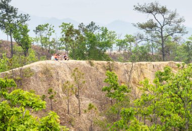 Pai, Mae Hong Son, Tayland-Nisan 09 2023: Genç gezginler, bu doğal oluşmuş, aşınmış doğal güzellik ve doğal güzellikte, sarp ve tehlikeli yollarda günbatımının tadını çıkarmak için uzak bir uçurumun tepesine tünediler..