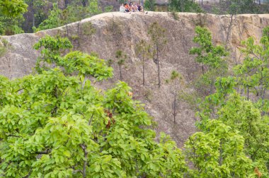 Pai, Mae Hong Son, Tayland-Nisan 09 2023: Genç gezginler, bu doğal oluşmuş, aşınmış doğal güzellik ve doğal güzellikte, sarp ve tehlikeli yollarda günbatımının tadını çıkarmak için uzak bir uçurumun tepesine tünediler..