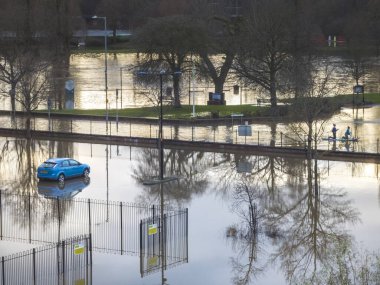 Worcester, Worcestershire, İngiltere-05 Ocak 2024: Su basmış bir otoparkta tek başına duran bir araba için, yerel halk normalde yaya yolu üzerinde yüzen bir kürek tahtası kullanıyor..