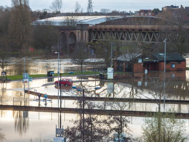 Worcester, Worcestershire, İngiltere-05 Ocak 2024: Su basmış bir otoparkta tek başına duran bir araba için, yerel halk normalde yaya yolu üzerinde yüzen bir kürek tahtası kullanıyor..