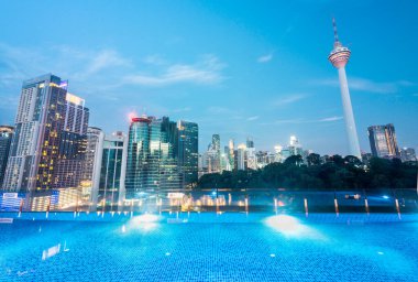 Stunning rootop nighttime view of KL city skyscrapers,brightly lit up at night, sleek pool in the foreground with stunning,high angle panoramic views of the modern city skyline. clipart