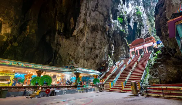 stock image Visitors go through the tall cave entrance,down a flight of stairs,into the vast interior,to admire the beautiful temple structures,built in 1920,and natural splendour of the limestone cave complex.