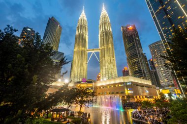 Kuala Lumpur, Malezya-23 Nisan 2024: KLCC Parkı 'nda akşam yaklaşırken, Suria KLCC Alışveriş Merkezi' nin dışındaki kaldırımda, pek çok ziyaretçi gelecek renkli müzik çeşmelerinin sergilenmesini bekliyor.