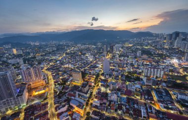 Aeriel view of the downtown area,with light trails from traffic below,and afterglow of sun behind distant hills, from the Observatory Deck of George Town's tallest building and prominent landmark. clipart