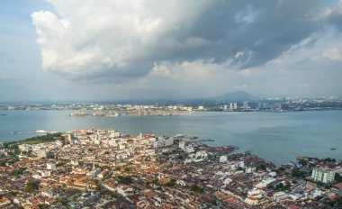 Şehrin ve Malacca Boğazı 'nın çarpıcı manzarası, George Town' un en yüksek binasının çatısından ve en belirgin simgesi, arka planda dramatik bulutlar, günbatımına yakın..