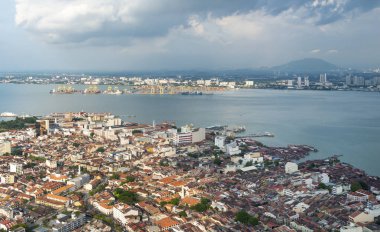 Şehrin ve Malacca Boğazı 'nın çarpıcı manzarası, George Town' un en yüksek binasının çatısından ve en belirgin simgesi, arka planda dramatik bulutlar, günbatımına yakın..