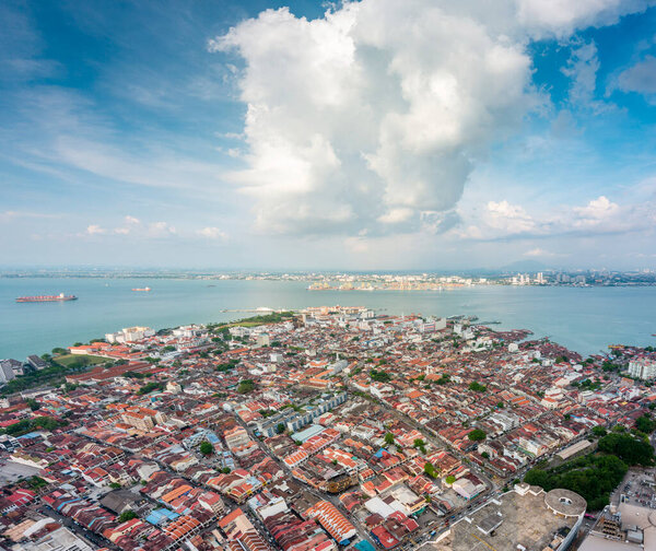 Stunning views of the city and Malacca Strait,from the rooftop of George Town's tallest building and prominent landmark,with dramatic clouds over mainland Malaysia in the background,close to sunset.