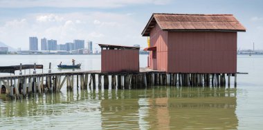 One of the Chinese Clan Jetties,popular with tourists,next to calm sea waters,a small jetty boardwalk in background, a fiishing boat and Malaysian mainland beyond.. clipart