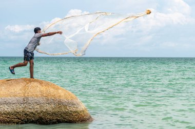 Penang, Malezya-30 Nisan 2023: Penang 'ın güney ucundaki bir sahilde, gizli bir mücevher olarak bilinen, güzel kumları, palmiyeleri, sakin ılık denizleri, mavi gökyüzü ve güneş ışığıyla yerel bir adam balık avlar..