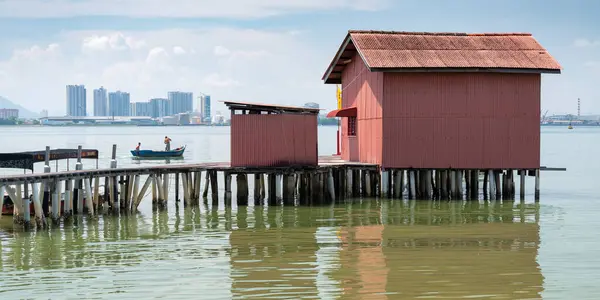 stock image One of the Chinese Clan Jetties,popular with tourists,next to calm sea waters,a small jetty boardwalk in background, a fiishing boat and Malaysian mainland beyond..