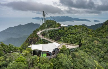 Winding over the forested peaks of Mat Cincang,second highest mountain in Langkawi,a major tourist site with awesome views across the islands,amazing steel structure and peice of modern engineering. clipart