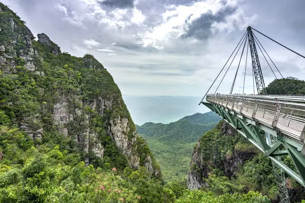 stock image Winding high over the forested peaks of Mat Cincang mountaini,a major tourist site with awesome views across the island,and sea beyond,an amazing cable stayed steel bridge,visited by many tourists.