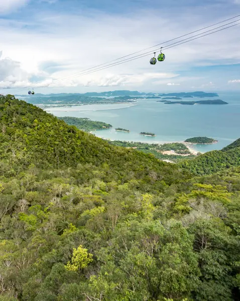 stock image Cable car gondolas travel to and fro the Middle and Upper stations,against a beautiful backdrop of Lankawis countryside,coastline and tree covered mountain peaks,a major tourist destination.