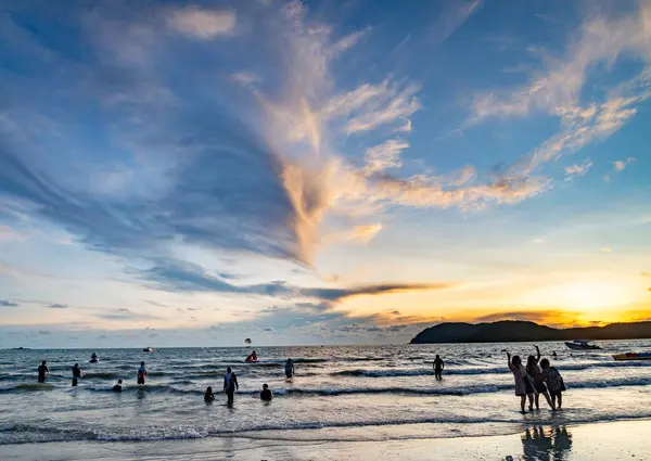 stock image Langkawi Island,Malaysia-May 05 2023:As the sun sets behind the small islands off Langkawi's west coast,many people congregate along the seashore, to watch the beautiful sundown,and play by the sea.