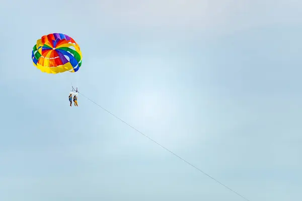 stock image Langkawi Island,Malaysia-May 05 2023:Tourists,high in the sky and above the sea, pay for parasail rides,pulled along by speed boats,in the late afternoon.