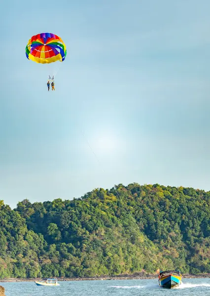 stock image Langkawi Island,Malaysia-May 05 2023:Tourists,high in the sky and above the sea, pay for parasail rides,pulled along by speed boats,in the late afternoon.