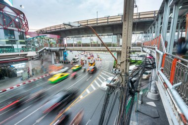 Yoğun şehir trafiğinin bulanık hareketi, kaldırımın altında hızla ilerlerken, aşağıdaki kalabalık şehrin üzerinden hızla geçen yüksek, yolcu dolu bir gökyüzü treni....