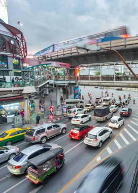 Bangkok, Tayland-08 Mayıs 2023: Şehir ulaşımı, trafik ışıklarında bekleyen çok sayıda araç ve yolcu dolu banliyö treni yüksek demiryolu boyunca hızla ilerliyor.