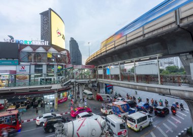 Bangkok,Thailand-May 08 2023:A passenger filled commuter train rushes past the Victory Mall at sunset,during rush hour. clipart