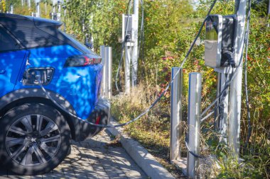 Worcester, İngiltere, İngiltere-17 Eylül 2024: Park halindeki yerli elektrik, pil motorlu araba, şarj cihazı takılı, gün boyunca şarj ediliyor, bir kamu tren istasyonu otoparkında.