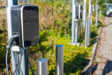 EV şarj noktası, bir tren istasyonunun otoparkında, kamu elektrikli aracının park yerinin yanında duruyor..