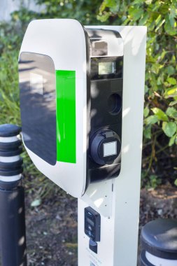 EV şarj noktası, bir tren istasyonunun otoparkında, kamu elektrikli aracının park yerinin yanında duruyor..