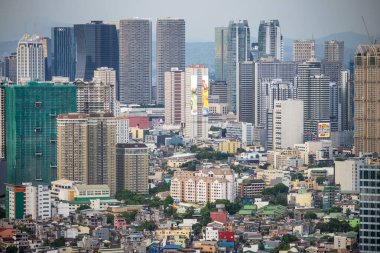 Manila, Luzon, Filipinler-19 Mayıs 2023: Batan güneş, yoğun, yoğun nüfuslu, yerleşim ve kurumsal yapıların çevresel karışımı olan şehir metropolüne sıcak bir ışık tutuyor.