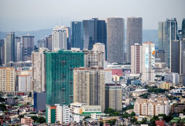 Manila, Luzon, Filipinler-19 Mayıs 2023: Batan güneş, yoğun, yoğun nüfuslu, yerleşim ve kurumsal yapıların çevresel karışımı olan şehir metropolüne sıcak bir ışık tutuyor.