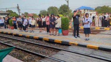 Hua Hin, Tayland-12 Şubat 2023: Bir tren garı bekçisi yeni açılan Hua Hin tren istasyonuna vardığında yeşil bayrak sallıyor.. 