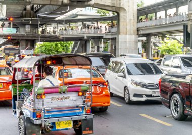 Bangkok, Tayland-Temmuz 03: 2024: Birçoğu banliyö yollarında yürüyen, yaya köprülerini, Skytrain istasyonlarını ve dükkanları birbirine bağlayan, çok sayıda sıkışık araç aşağıda yavaşça hareket ediyor.