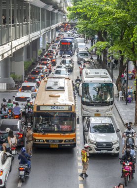 Tayland - Temmuz 03: 2024: Trafik polisleri araçların akışını kontrol etmeye çalışırken ve yayalar komşu kaldırım boyunca yürüdükçe, öğleden sonra trafiği yavaş ilerliyor.