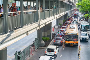 Tayland - Temmuz 03: 2024: Trafik polisleri araçların akışını kontrol etmeye çalışırken ve yayalar komşu kaldırım boyunca yürüdükçe, öğleden sonra trafiği yavaş ilerliyor.