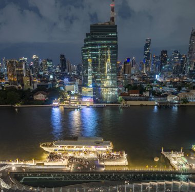 Bangkok, Tayland-02 Temmuz: Nehir yaşamının gece sahnesi, aydınlatılmış şehir silueti ve nehir tekneleri, en üst kattan, çok amaçlı ikonik bir binanın açık terası, nehir kenarı binası.